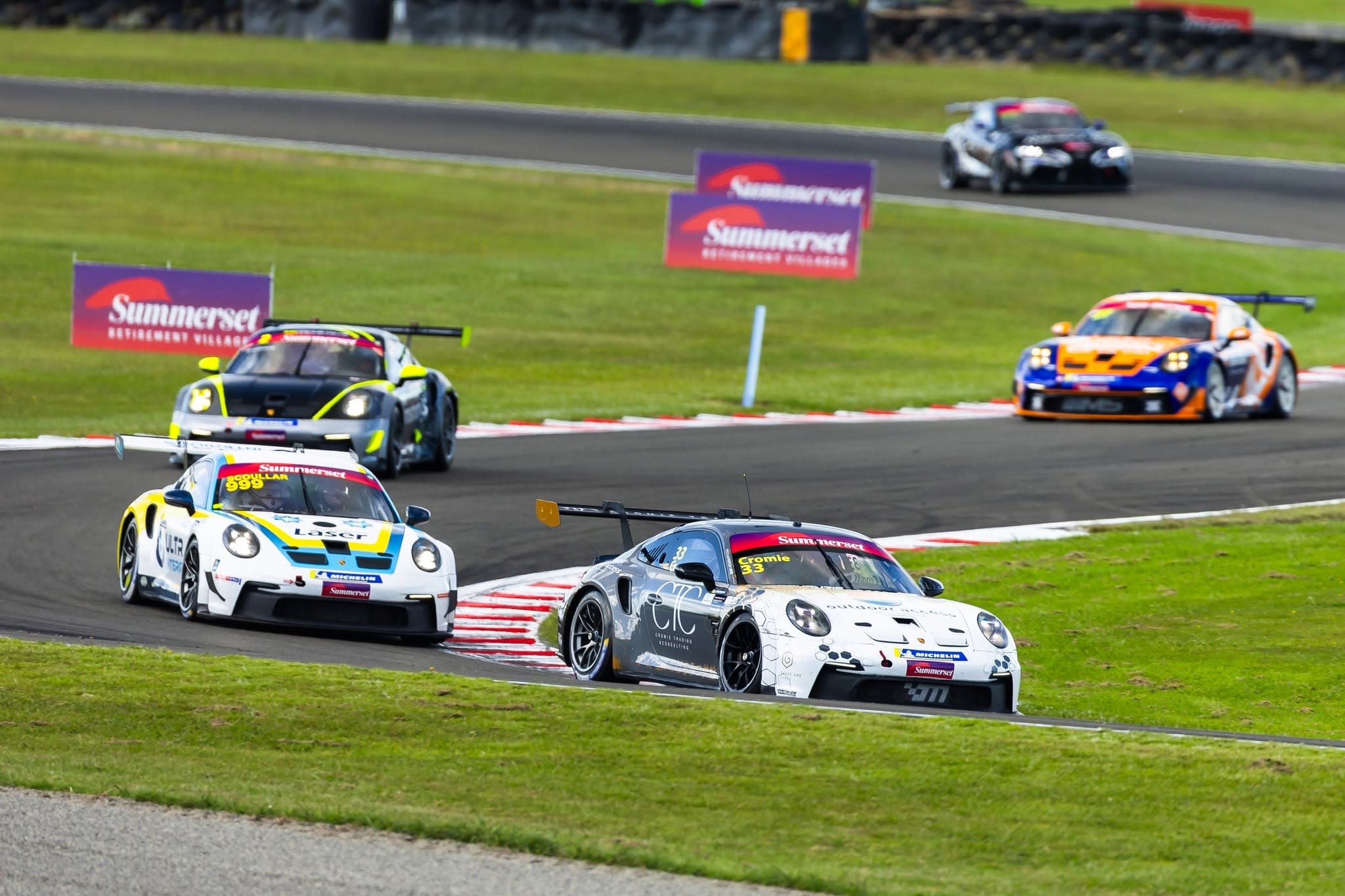 GT cars sweep through a corner past Summerset trackside signage